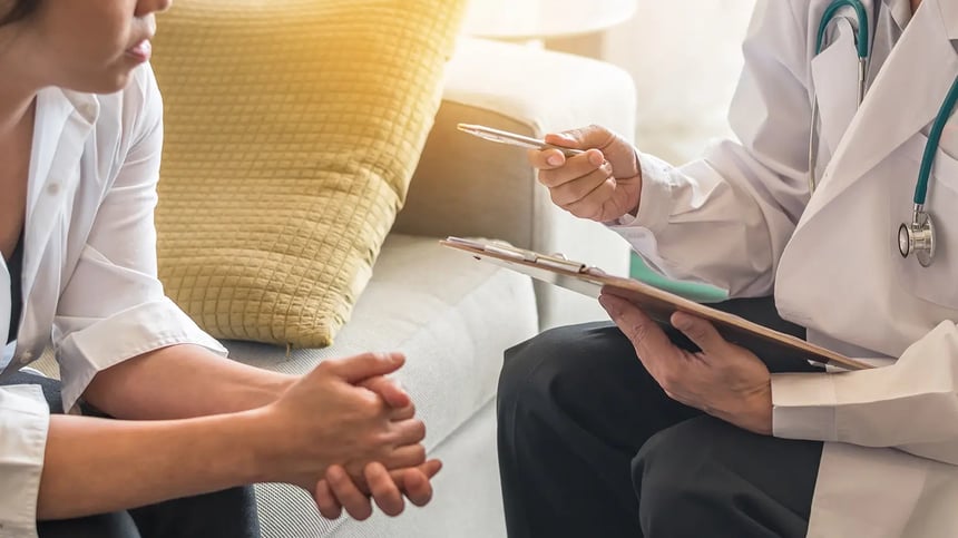 A doctor reviews notes with a patient during a consultation to help determine which breast lift technique may suit their anatomy