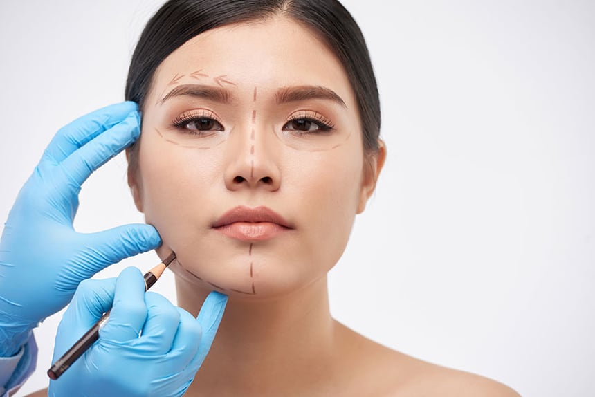 A plastic surgeon marking treatment areas on a patient’s face before surgery.